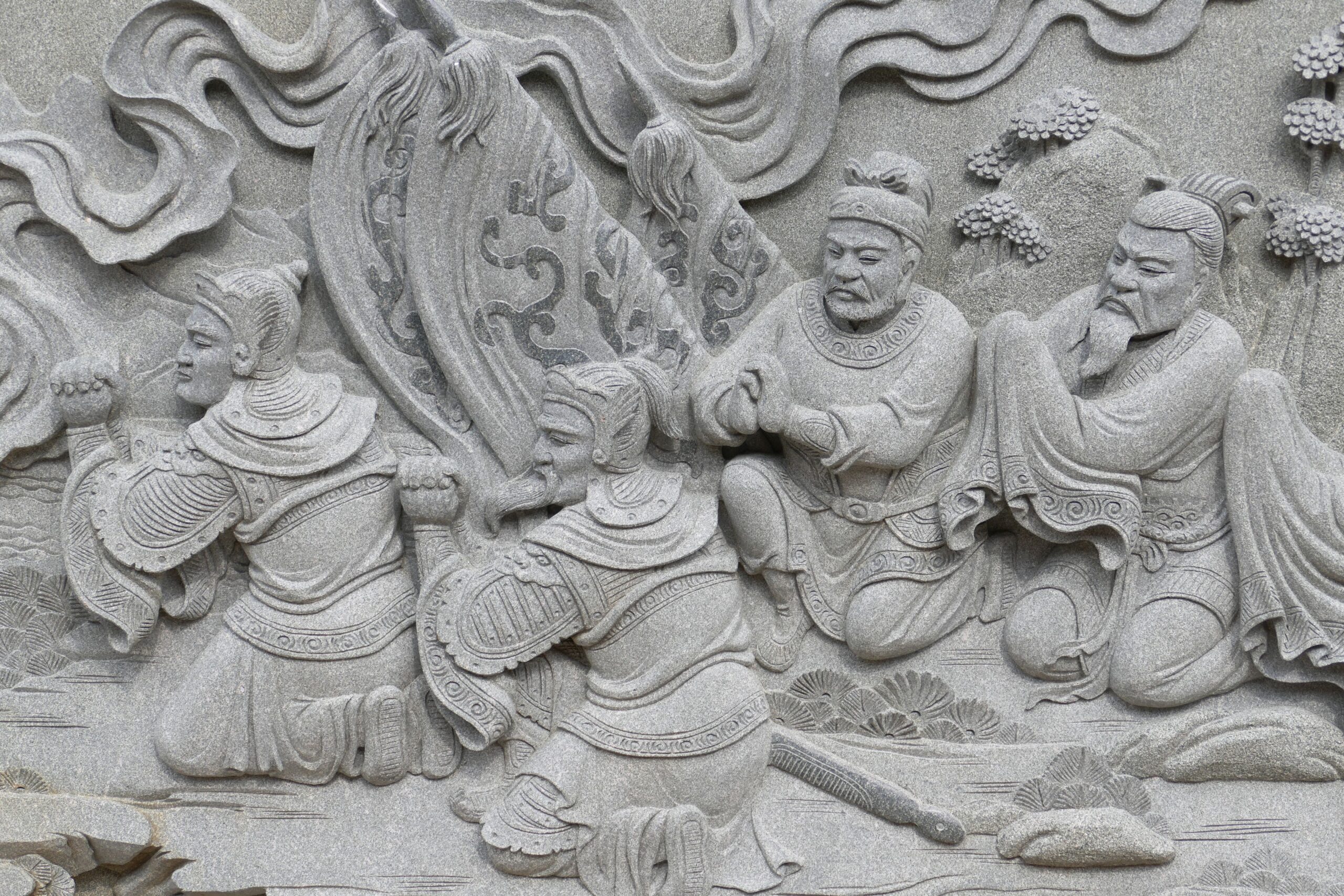 Intricate stone carving depicting ancient Daoist philosophers and warriors in traditional Chinese attire. This symbolizes the importance of philosophy and thought, especially in times of battle.